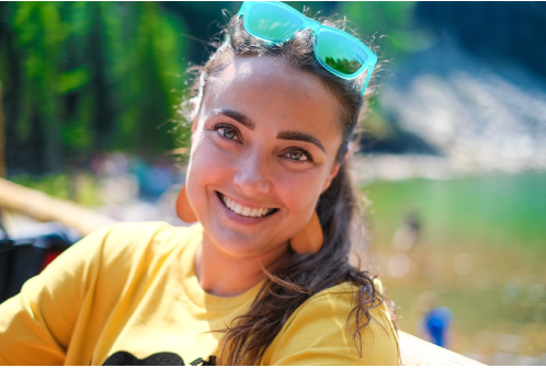 Grace in a yellow t-shirt shirt with green sunglasses on her head in front of Lake Agnes in Banff National Park 