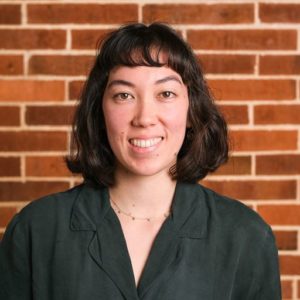 photo of Nicole smiling in front of a brick wall