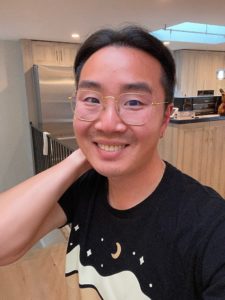 A Taiwanese man in glasses and black tee shirt smiling