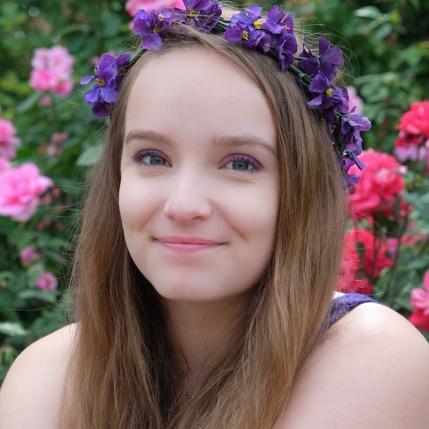 A white-presenting person with a wreath of flowers in their hair