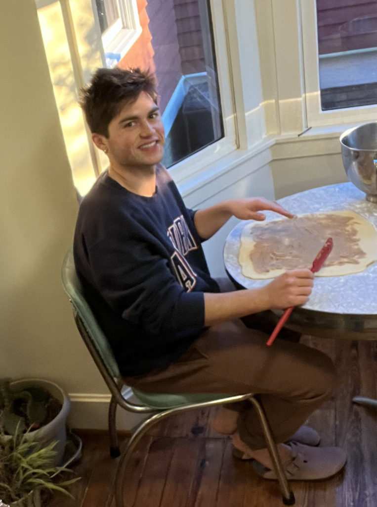 Michael, a guy with brown hair and rosy cheeks making sticky buns for his family on Christmas eve