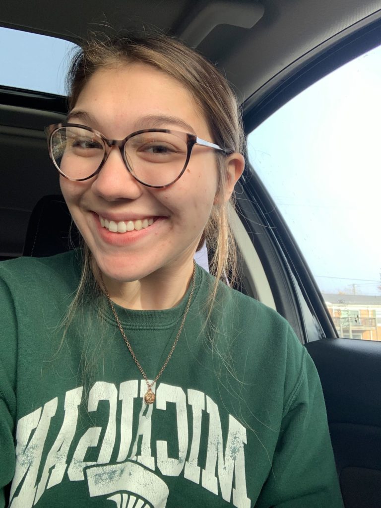 A white woman with glasses wearing a Michigan state sweatshirt